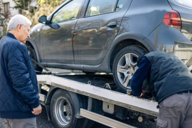 man inspects car being towed